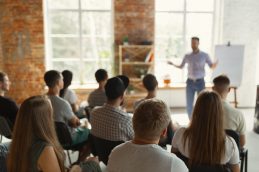 Uma sala em que está ocorrendo uma palestra, aparentando ser uma organização que acredita no poder dos webinars e workshops em uma empresa para melhorar os resultados